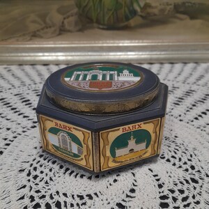 May include: A vintage, blue and gold, rotating, hexagonal, decorative box with images of the VDNKh pavilions in Moscow, Russia. The box has the text "ВДНХ" and "ПАВИЛЬОН-ЗЕМЛЕДЕЛИЕ" on it.