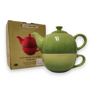 Könnte beinhalten: Ein grünes Keramik-Tee-für-eins-Set, bestehend aus einer Teekanne und einer Tasse. Die Teekanne steht auf der Tasse. Links befindet sich ein Karton mit einer roten Teekannen-Illustration. Der Text auf der Box lautet "Tea for One Set".