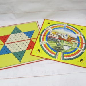 Puede incluir: Dos tableros de juego vintage. Un tablero es una estrella amarilla con un patrón de cuadrícula rojo, azul y verde. El otro tablero es amarillo con una pista de carreras circular con caballos y jinetes. El texto en la pista de carreras dice "24" y "27".