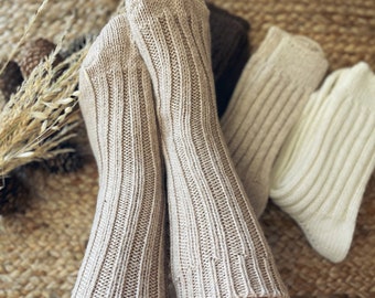 May include: A pair of beige ribbed knit socks. The socks are made of a soft, comfortable material and have a relaxed fit.