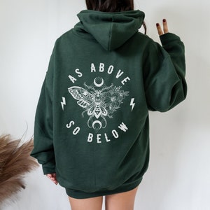 May include: A dark green hooded sweatshirt with a white graphic print on the back. The graphic features a moth with wings spread, a crescent moon, and the text "As Above So Below".