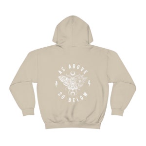 May include: A beige hoodie with a white graphic print of a moth, flowers, and crescent moon. The text "As Above So Below" is printed in a circle around the graphic.