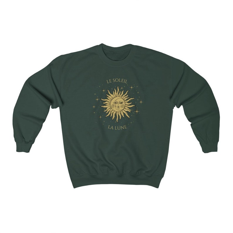 Peut inclure: Un sweat-shirt vert fonc&eacute; avec un motif soleil et lune dor&eacute;. Le soleil a un visage et est entour&eacute; d'&eacute;toiles. Le texte "LE SOLEIL" est au-dessus du soleil et "LA LUNE" est en dessous du soleil.