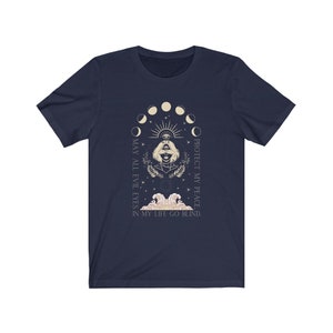 May include: Navy blue t-shirt featuring a graphic with a woman's face, an eye, and moon phases. The text reads "MAY ALL EVIL EYES IN MY LIFE GO BLIND. PROTECT MY PEACE."