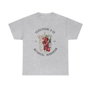 May include: A gray t-shirt with a graphic design of a skeleton with red roses and pomegranates inside the ribcage. The text around the graphic reads "PERSEPHONE & CO EST. 1989 BOTANICAL HERBARIUM".