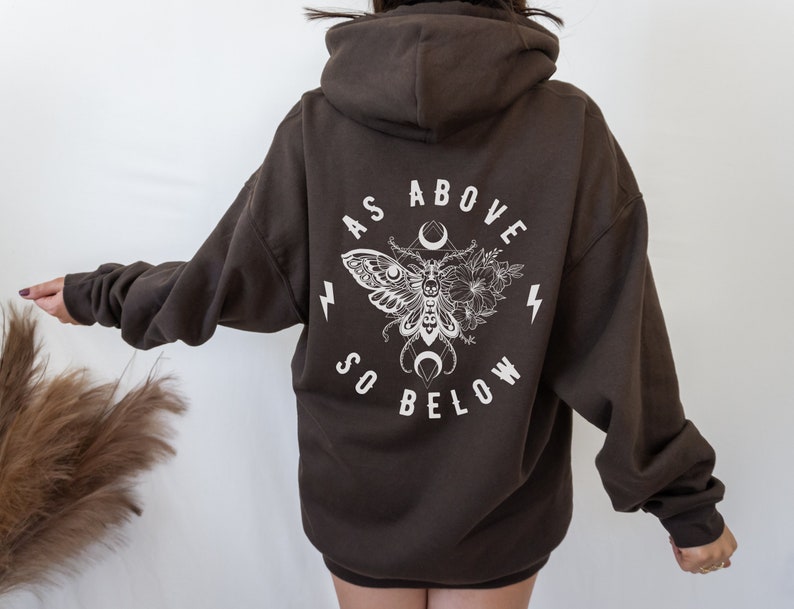 May include: A brown hooded sweatshirt with a white graphic print of a moth, flowers, and the text "As Above So Below".
