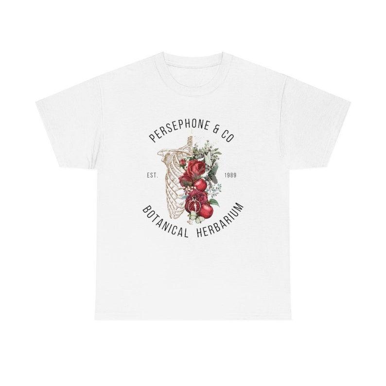 May include: White t-shirt with a graphic design of a skeleton with red roses and pomegranates inside the ribcage. The text "PERSEPHONE & CO. EST. 1989 BOTANICAL HERBARIUM" surrounds the graphic.