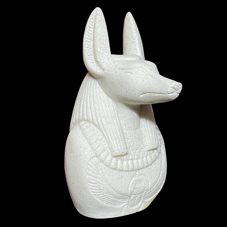 May include: White marble statue of an Egyptian god Anubis with a jackal head, wearing a traditional headdress and collar.