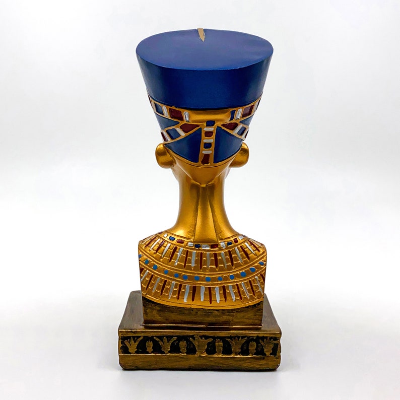 Peut inclure: Buste en or d'une reine &eacute;gyptienne portant une coiffe bleue avec des accents rouges et dor&eacute;s. La statue est sur une base dor&eacute;e avec des d&eacute;tails d&eacute;coratifs.