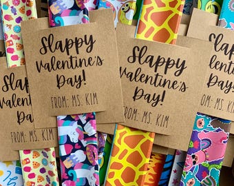 May include: A collection of colorful bookmarks with various patterns, including donuts, giraffes, and unicorns. Each bookmark is paired with a brown card that reads "Slappy Valentine's Day! From: Ms. Kim."