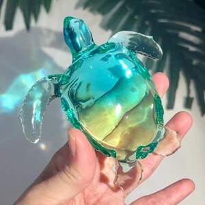 Op de afbeelding: Een glazen zeeschildpad-figuur met een gradiënt van blauwe en groene kleuren. De schildpad is doorschijnend en heeft een gedetailleerde schild.