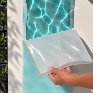 May include: A rectangular silicone mould with a wavy, rippled surface texture. The mould is translucent white and flexible, designed for casting resin or other materials to create a water-like effect with light-refracting patterns.
