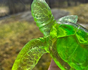 May include: A green glass sea turtle figurine with a detailed shell and flippers.