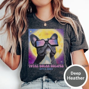 May include: A dark heather grey t-shirt with a graphic of a French bulldog wearing sunglasses in front of a yellow sun. The text "TOTAL SOLAR ECLIPSE" and "April 8, 2024" is printed below the graphic.