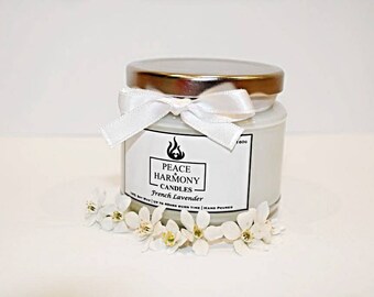 May include: A white candle jar with a gold lid and a white ribbon tied around it. The jar has a label that says "Peace & Harmony Candles" and "French Lavender".