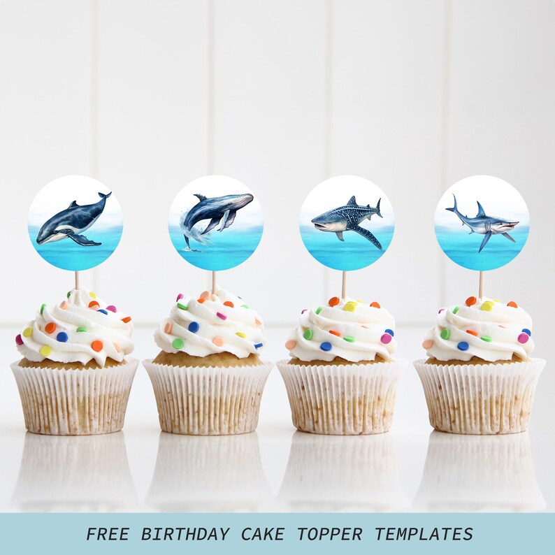 May include: Four cupcakes with white frosting and colorful sprinkles. Each cupcake has a round topper with a watercolor image of a whale or shark above blue water. The text "FREE BIRTHDAY CAKE TOPPER TEMPLATES" is at the bottom.