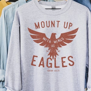 May include: Gray sweatshirt with a brown eagle graphic and the text "Mount Up With Wings As Eagles Isaiah 40:31".