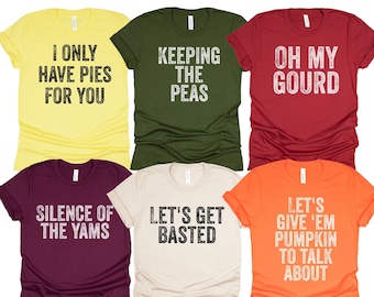 Op de afbeelding: Zes verschillende T-shirts met Thanksgiving-thema tekst erop gedrukt. De shirts zijn in verschillende kleuren, waaronder geel, groen, rood, bordeauxrood, beige en oranje.