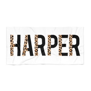 May include: White beach towel with the name "HARPER" printed in black letters. Each letter has a leopard print pattern behind it.