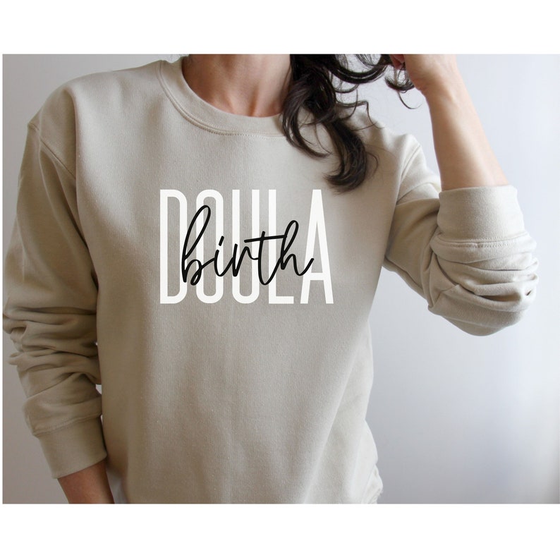 K&ouml;nnte beinhalten: Ein beiger Pullover mit dem Aufdruck "Doula birth" in Schwarz und Wei&szlig; auf der Vorderseite.