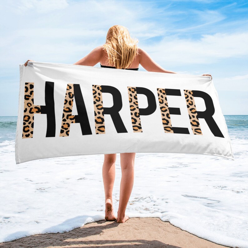 May include: White beach towel with the name "HARPER" printed in black letters. The letters are outlined with a leopard print pattern.