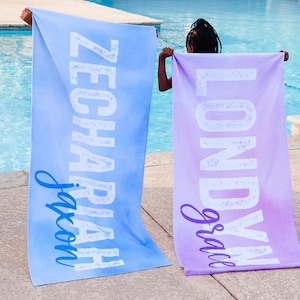 Pode incluir: Duas toalhas de praia personalizadas com os nomes "Jaxon" e "Gracie" impressos em branco sobre um fundo azul e roxo degrad&ecirc;.
