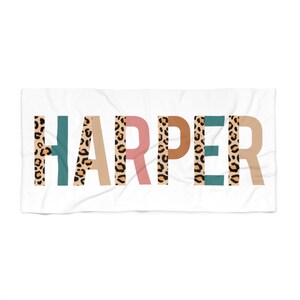 May include: White beach towel with the name "HARPER" printed in large, bold letters. Each letter is filled with a leopard print pattern and has a different colored background: teal, beige, pink, brown, teal, beige.