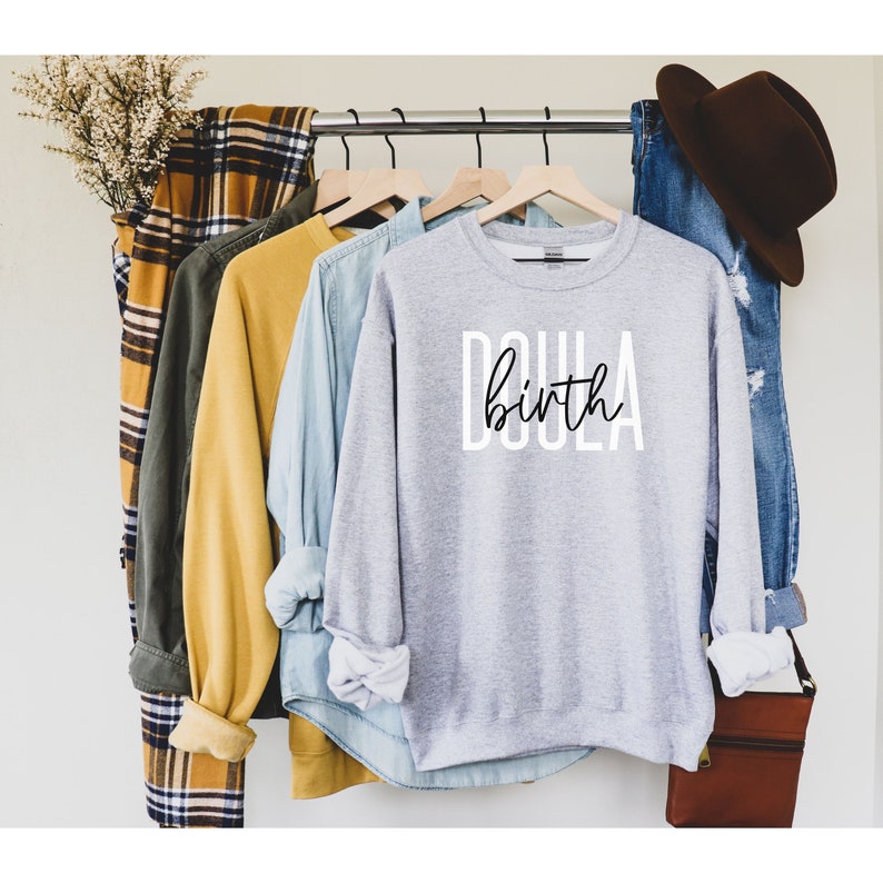K&ouml;nnte beinhalten: Grauer Pullover mit dem Text "Doula birth" in Schwarz und Wei&szlig;.