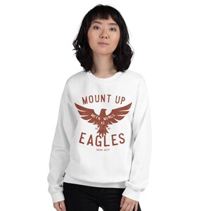 May include: White sweatshirt with a brown eagle graphic and the text "Mount Up With Wings As Eagles Isaiah 40:31".