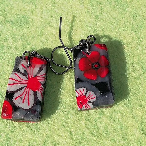 Boucles d'oreilles en pâte polymère fleurs en millefiori avec différents tons de rouges, gris sur fond noir, paillettes.