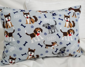 May include: A rectangular cushion with a pale blue backdrop, decorated with cartoon dogs in brown, white, and grey. The design includes paw prints, bones, and the words "BARK!" and "SNIFF!"