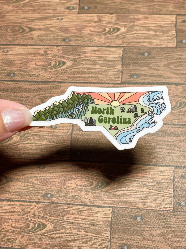 North Carolina sticker featuring Charlotte, Raleigh/Durham area, mountains, beaches, sunshine, and farms. Sticker is in the shape of NC with a white offset.