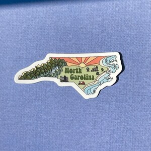 North Carolina sticker featuring Charlotte, Raleigh/Durham area, mountains, beaches, sunshine, and farms. Sticker is in the shape of NC with a white offset.