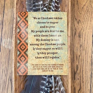 May include: A rectangular card with text from Choctaw Chief George W. Harkins, framed by feathers. The card features a quote about freedom and suffering, with an orange and brown geometric border. The text is set against a tan background.