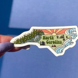 North Carolina sticker featuring Charlotte, Raleigh/Durham area, mountains, beaches, sunshine, and farms. Sticker is in the shape of NC with a white offset.