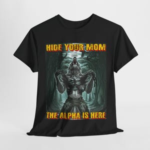 Puede incluir: Camiseta negra con un gráfico de un hombre lobo con el texto "Hide Your Mom The Alpha Is Here" impreso en ella.