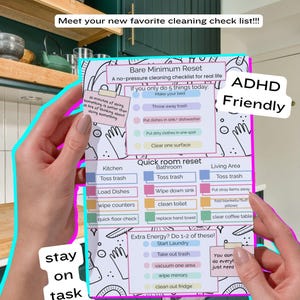 May include: A colorful cleaning checklist with the text "Bare Minimum Reset" and "ADHD Friendly." The checklist includes tasks for the kitchen, bathroom, and living area, with additional tasks for extra energy. The image is held by a person.