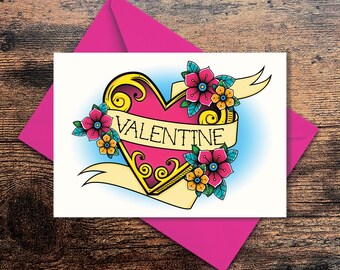 May include: A white card featuring a pink heart tattoo design. The heart is surrounded by flowers and a banner that reads "VALENTINE".