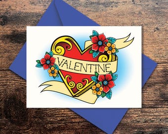 May include: A white card featuring a red heart with a gold outline and the word "VALENTINE" on a banner. The heart is surrounded by flowers in red, yellow, and blue.