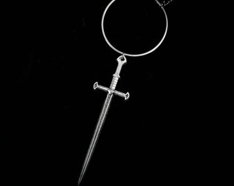 May include: A silver necklace with a circular pendant and a sword charm hanging from it.