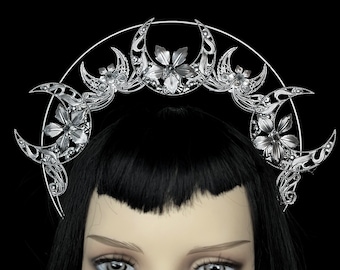 May include: Silver crown with a crescent moon design and floral accents. The crown is worn on a mannequin with black hair.
