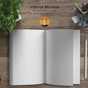May include: A white notebook with a dotted pattern on the pages is open and lying flat on a wooden surface. The notebook is surrounded by a pencil, a white eraser, and a container of pens.