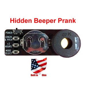 May include: A small black circuit board with a black button, a silver battery holder, and a black speaker. The board has the text "POWER", "LENGTH & PITCH", "+2 HOURS", and "MODE SELECT" printed on it. The speaker has the text "07 K" and "muRata" printed on it. The board is labeled "Hidden Beeper Prank".