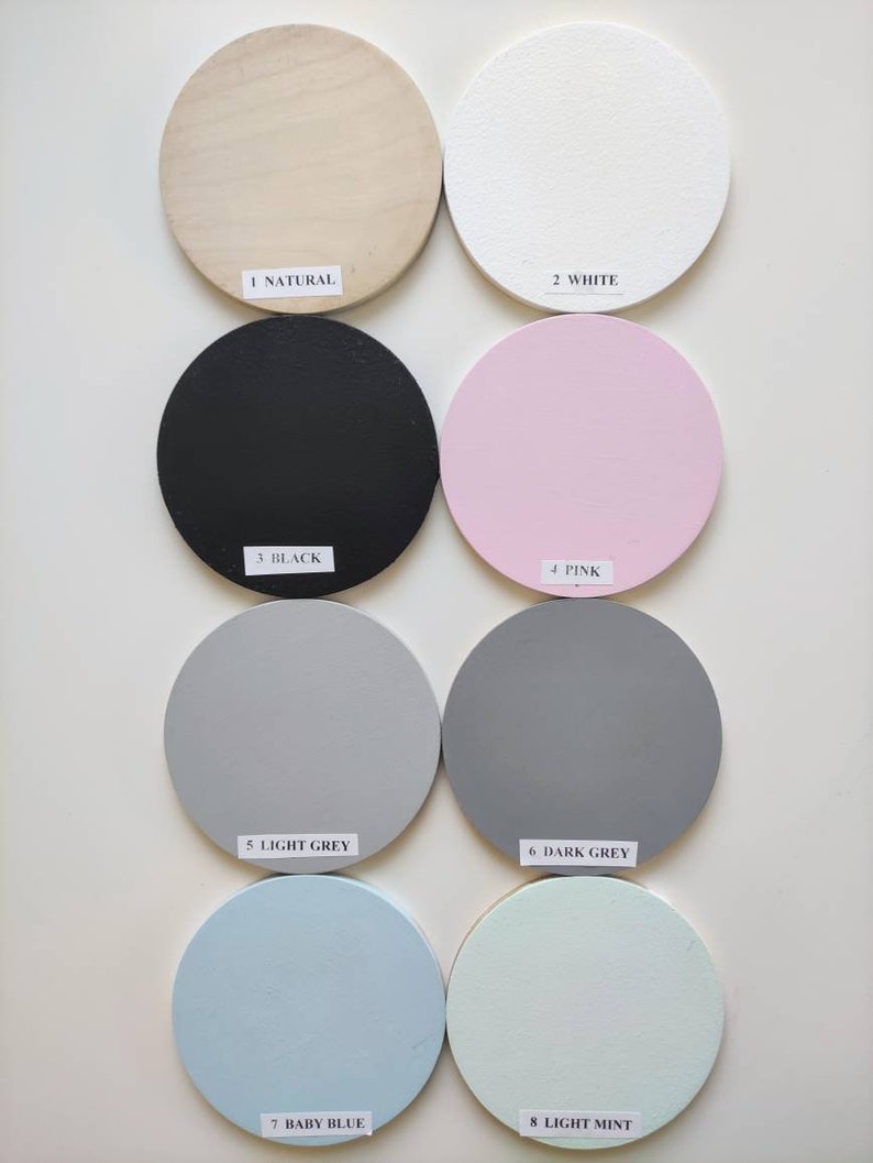 May include: Eight round wooden discs painted in different colors: natural wood, white, black, pink, light gray, dark gray, baby blue, and light mint. Each disc has a number and color name printed below it.