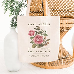 May include: A white tote bag with a floral design and the text "Jane Austen 1813 Derbyshire Pride & Prejudice A Dance of Courtship & Misunderstandings"