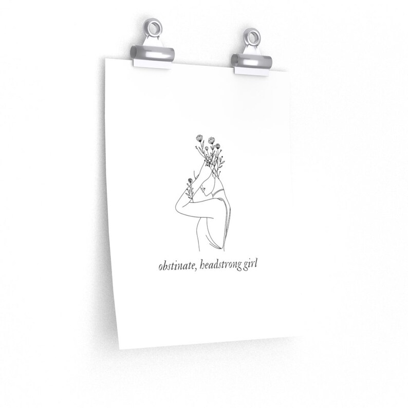 May include: Line art print of a woman with flowers growing from her head. The text "obstinate, headstrong girl" is below the image.