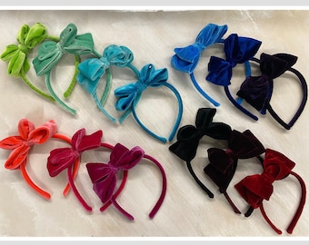 May include: Assortment of velvet headbands with bows in various colors, including green, blue, red, and black.