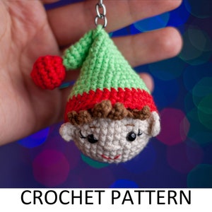 Könnte beinhalten: Ein grünes und rotes gehäkeltes Elfenornament mit einem weißen Gesicht und braunen Haaren. Der Elf hält einen kleinen roten Ball in der Hand.