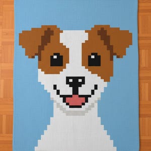 May include: A blue knitted blanket featuring a pixelated image of a smiling dog's face. The dog has brown ears, black eyes, a black nose, and a pink tongue. The background of the blanket is light blue.