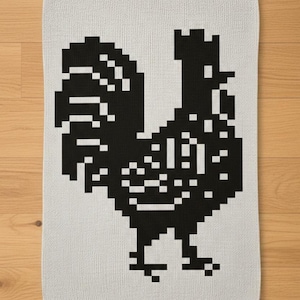 May include: A white kitchen towel featuring a pixelated black rooster design. The rooster is depicted in a blocky, retro style, with a detailed silhouette. The towel is rectangular and likely made of cotton.
